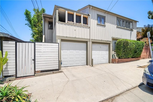 2511 W 5th St, Los Angeles, CA 90057 - view of front facade with board and batten siding, an attached garage, concrete driveway, and a gate