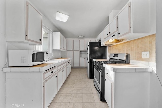 3648 Mira Pacific Dr, Oceanside, CA 92056 - kitchen featuring stainless steel gas range, white microwave, tile countertops, and decorative backsplash