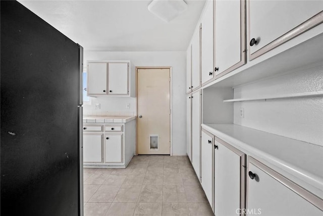 3648 Mira Pacific Dr, Oceanside, CA 92056 - kitchen with freestanding refrigerator, white cabinetry, light countertops, open shelves, and light tile patterned flooring
