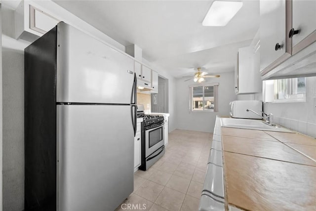 3648 Mira Pacific Dr, Oceanside, CA 92056 - kitchen featuring appliances with stainless steel finishes, white cabinets, exhaust hood, light tile patterned flooring, and a ceiling fan