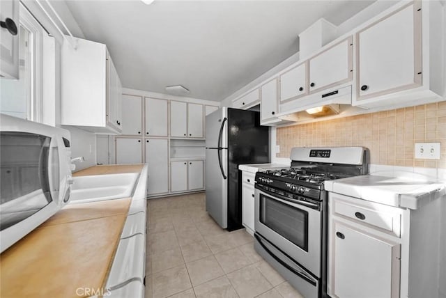 3648 Mira Pacific Dr, Oceanside, CA 92056 - kitchen with appliances with stainless steel finishes, under cabinet range hood, light countertops, white cabinetry, and light tile patterned floors