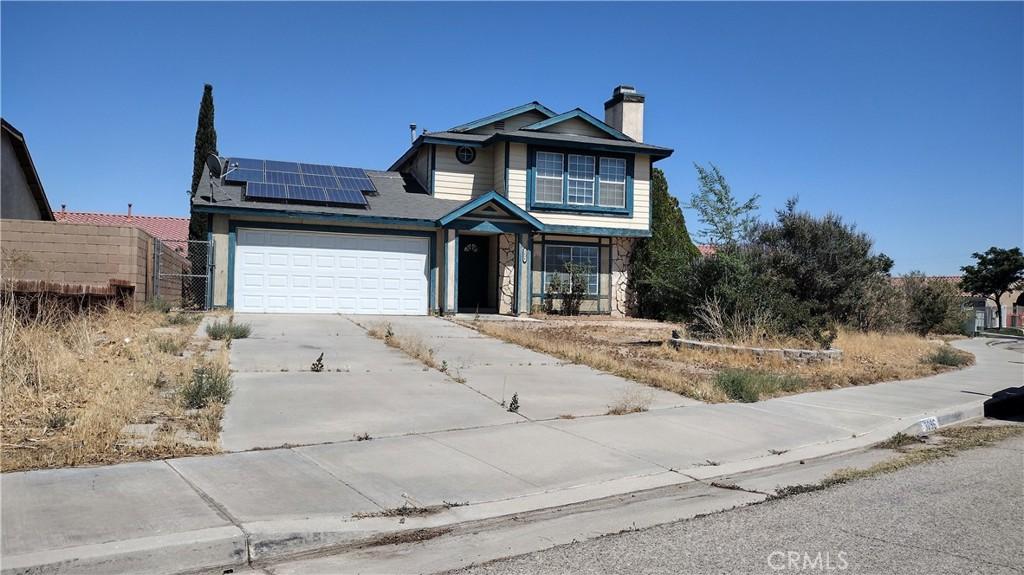 3096 Sedona St, Rosamond, CA 93560 - traditional-style house with solar panels, a chimney, a garage, driveway, and stone siding