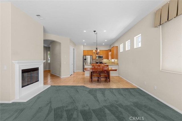 1790 N Forest Oaks Dr, Beaumont, CA 92223 - dining space with light carpet, arched walkways, light tile patterned floors, recessed lighting, and a glass covered fireplace