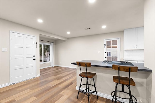 716 N Tulare Way, Upland, CA 91786 - kitchen featuring a breakfast bar, dark countertops, white cabinets, light wood-type flooring, and recessed lighting