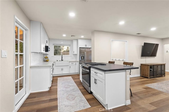 716 N Tulare Way, Upland, CA 91786 - kitchen with appliances with stainless steel finishes, recessed lighting, decorative backsplash, dark wood finished floors, and a kitchen bar
