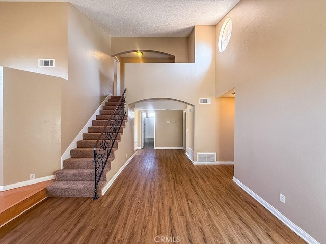 16702 Canoe Cv, Moreno Valley, CA 92551 - foyer with arched walkways, wood finished floors, a textured ceiling, stairs, and a high ceiling