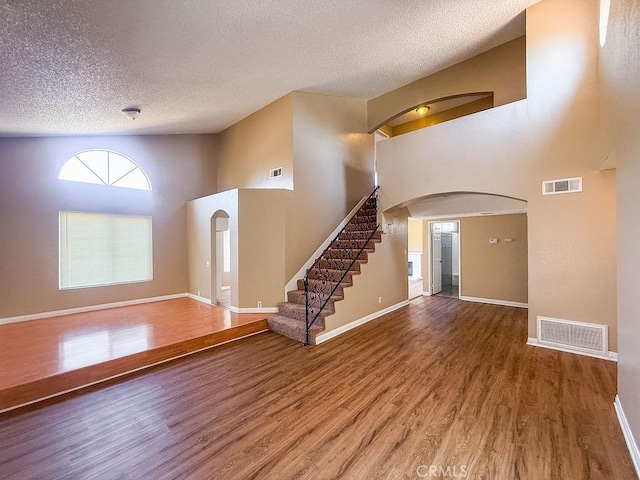 16702 Canoe Cv, Moreno Valley, CA 92551 - foyer featuring a textured ceiling, wood finished floors, arched walkways, a towering ceiling, and stairway