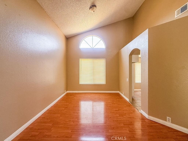 16702 Canoe Cv, Moreno Valley, CA 92551 - unfurnished room featuring arched walkways, wood finished floors, lofted ceiling, a textured ceiling, and a textured wall