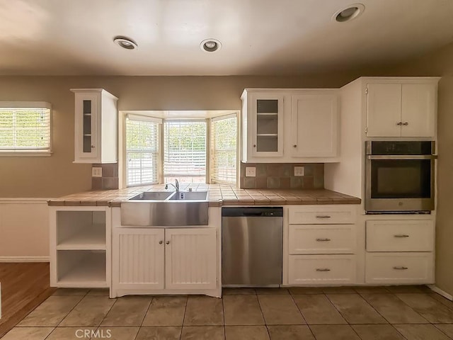 409 N Elwood Ave, Glendora, CA 91741 - kitchen featuring appliances with stainless steel finishes, tile counters, white cabinets, and glass insert cabinets