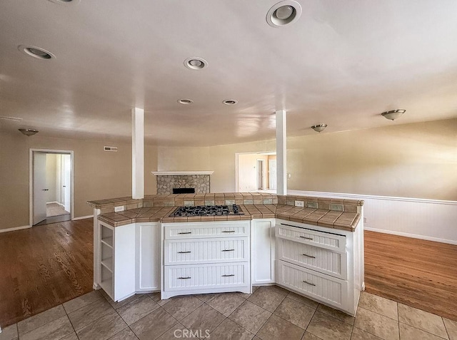 409 N Elwood Ave, Glendora, CA 91741 - kitchen with stainless steel gas cooktop, white cabinetry, open floor plan, tile countertops, and a fireplace