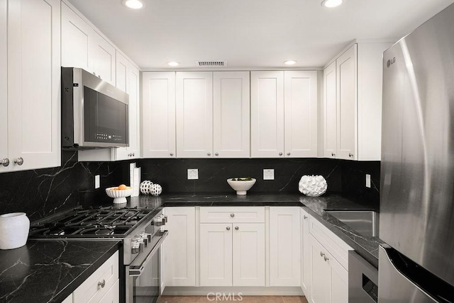 4411/2 Goldenrod Ave, Corona Del Mar, CA 92625 - kitchen featuring appliances with stainless steel finishes, recessed lighting, backsplash, white cabinets, and dark stone counters