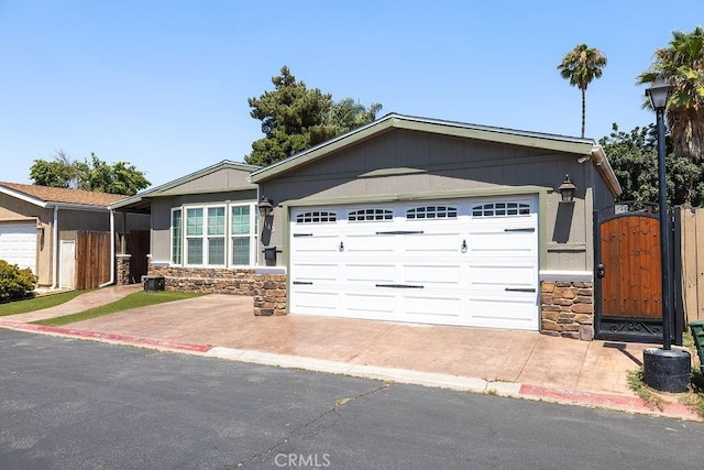 700 E Washington St Unit 143, Colton, CA 92324 - ranch-style house featuring stone siding, a garage, concrete driveway, and a gate