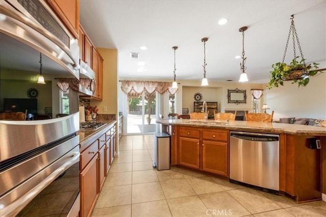 19247 Mountain Shadow Ln, Perris, CA 92570 - kitchen featuring appliances with stainless steel finishes, brown cabinets, decorative light fixtures, recessed lighting, and light tile patterned floors
