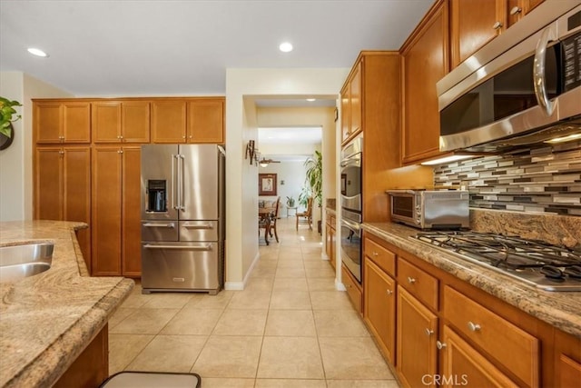 19247 Mountain Shadow Ln, Perris, CA 92570 - kitchen with stainless steel appliances, light tile patterned floors, decorative backsplash, brown cabinets, and recessed lighting
