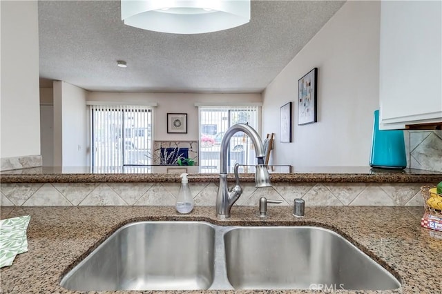 7302 Bright Ave Unit B, Whittier, CA 90602 - kitchen view of light stone counters, backsplash, a textured ceiling, and white cabinets