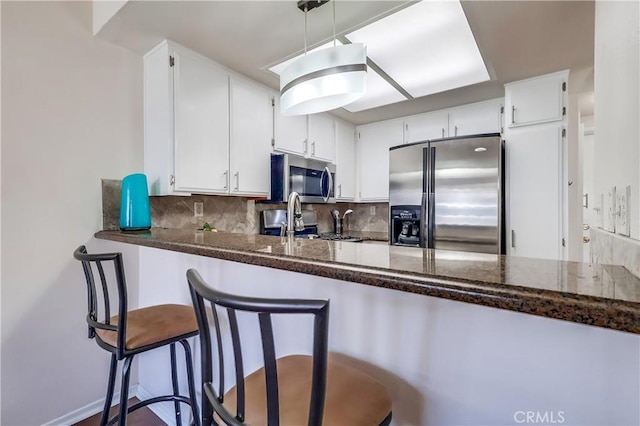 7302 Bright Ave Unit B, Whittier, CA 90602 - kitchen featuring stainless steel appliances, decorative backsplash, white cabinetry, and a peninsula