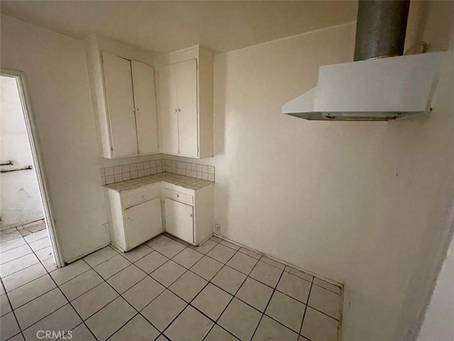 11250 Victory Blvd, North Hollywood, CA 91606 - kitchen with tile countertops, ventilation hood, light tile patterned flooring, white cabinetry, and decorative backsplash
