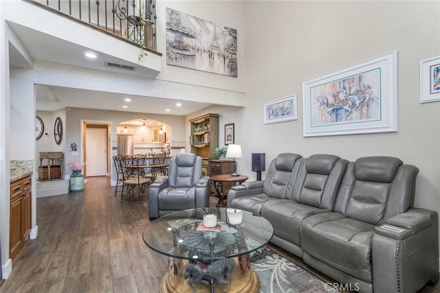 23130 Yvette Ln, Valencia, CA 91355 - living room featuring arched walkways, dark wood-type flooring, a towering ceiling, and recessed lighting