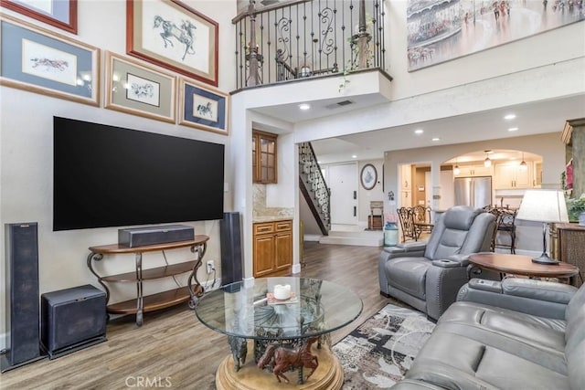 23130 Yvette Ln, Valencia, CA 91355 - living room with light wood finished floors, arched walkways, stairway, recessed lighting, and a towering ceiling