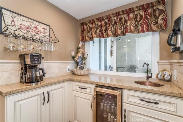 23130 Yvette Ln, Valencia, CA 91355 - kitchen featuring beverage cooler, light stone countertops, white cabinetry, and a wainscoted wall