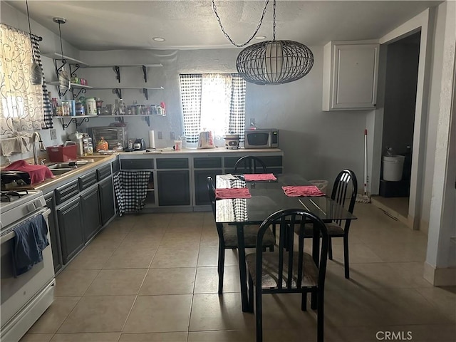 3938 Kreuer Rd, Phelan, CA 92371 - kitchen with white gas range, stainless steel microwave, light tile patterned flooring, and light countertops