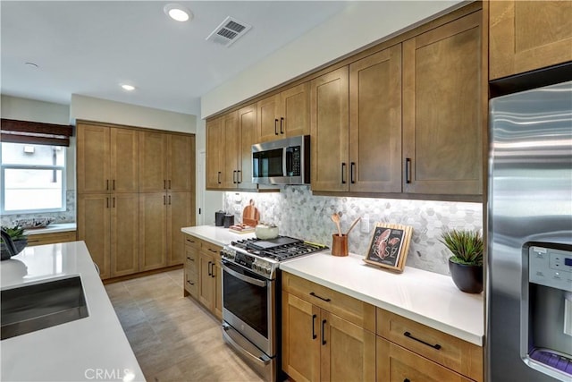 17163 Kent St, Hesperia, CA 92345 - kitchen featuring appliances with stainless steel finishes, light countertops, backsplash, brown cabinetry, and recessed lighting
