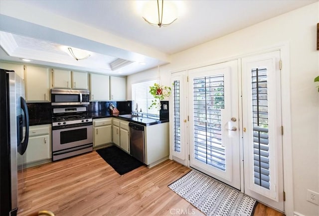 5260 W Palmer Dr, Banning, CA 92220 - kitchen featuring stainless steel appliances, a tray ceiling, dark countertops, and light wood-style floors