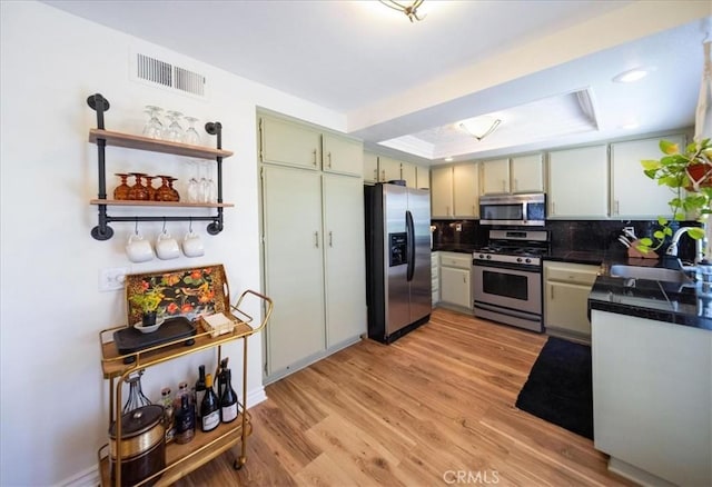 5260 W Palmer Dr, Banning, CA 92220 - kitchen featuring appliances with stainless steel finishes, a tray ceiling, light wood-style floors, tasteful backsplash, and tile counters