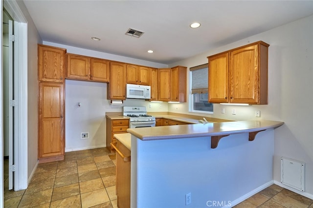1660 Snowberry Rd, Beaumont, CA 92223 - kitchen featuring white appliances, brown cabinetry, a peninsula, recessed lighting, and light countertops