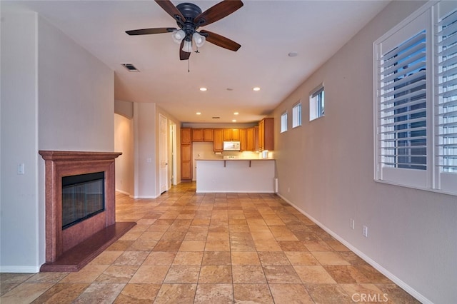 1660 Snowberry Rd, Beaumont, CA 92223 - unfurnished living room featuring light stone finish floors, a ceiling fan, a glass covered fireplace, and recessed lighting