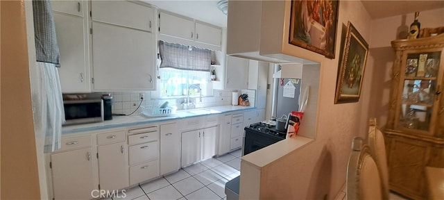 1605 S Birch St, Santa Ana, CA 92707 - kitchen featuring stainless steel microwave, light countertops, decorative backsplash, and white cabinetry
