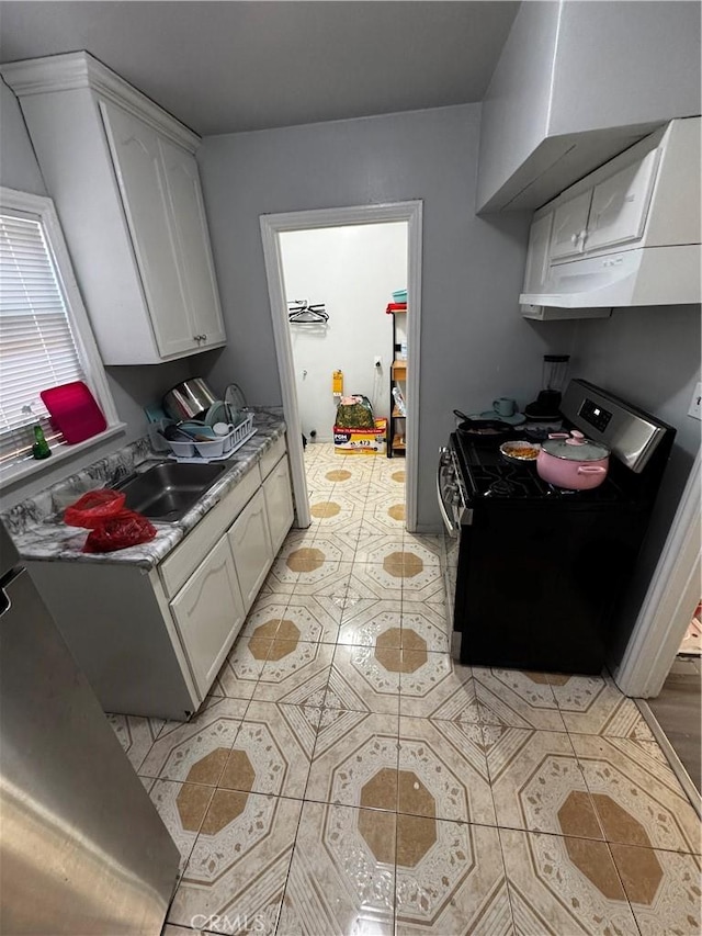8648 Chestnut Ave, South Gate, CA 90280 - kitchen featuring gas range oven, light tile patterned floors, white cabinets, under cabinet range hood, and light countertops