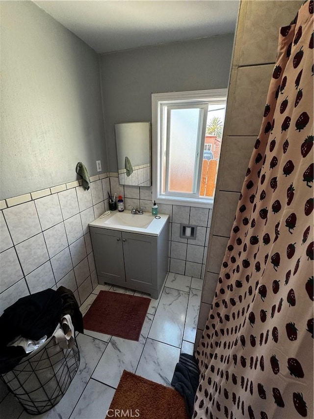 8648 Chestnut Ave, South Gate, CA 90280 - bathroom featuring tile walls, tiled shower, marble finish floors, vanity, and a wainscoted wall