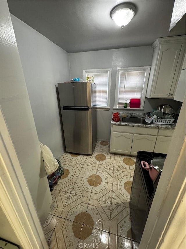 8648 Chestnut Ave, South Gate, CA 90280 - kitchen featuring freestanding refrigerator, range, light tile patterned floors, and white cabinetry