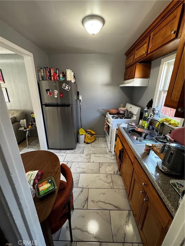 8648 Chestnut Ave, South Gate, CA 90280 - kitchen featuring freestanding refrigerator, light marble finish floors, brown cabinetry, white gas stove, and under cabinet range hood