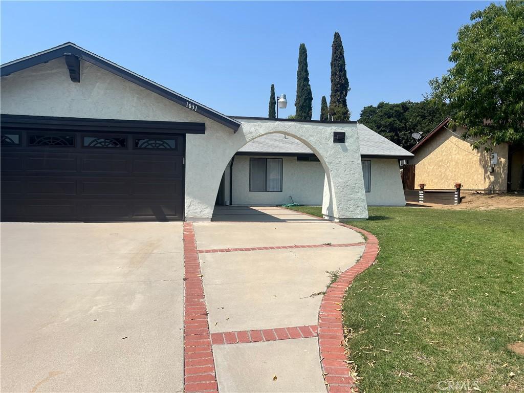 1031 Athena Ct, Riverside, CA 92507 - ranch-style house featuring stucco siding, a front lawn, a garage, and driveway