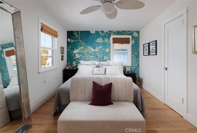 31907 9th Ave, Laguna Beach, CA 92651 - bedroom featuring wallpapered walls, an accent wall, multiple windows, light wood-type flooring, and ceiling fan