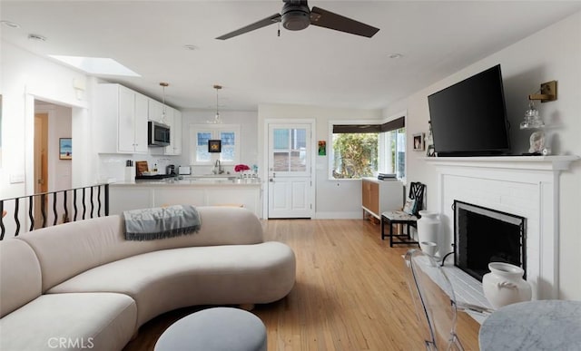 31907 9th Ave, Laguna Beach, CA 92651 - living area featuring light wood-style flooring, a ceiling fan, a fireplace, and a skylight