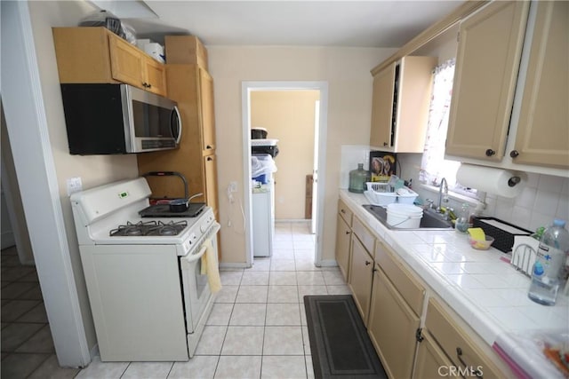 2432 N Eastern Ave, Los Angeles, CA 90032 - kitchen with white gas stove, stainless steel microwave, tile countertops, decorative backsplash, and light tile patterned floors