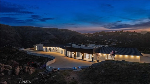109 Buckskin Rd, Bell Canyon, CA 91307 - back of property at dusk featuring a mountain view, a patio area, and stucco siding