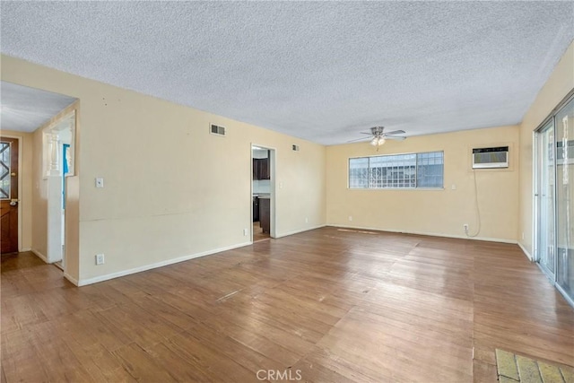 502 Tasman Ave, Pomona, CA 91767 - unfurnished living room with wood finished floors, a textured ceiling, ceiling fan, an AC wall unit, and plenty of natural light