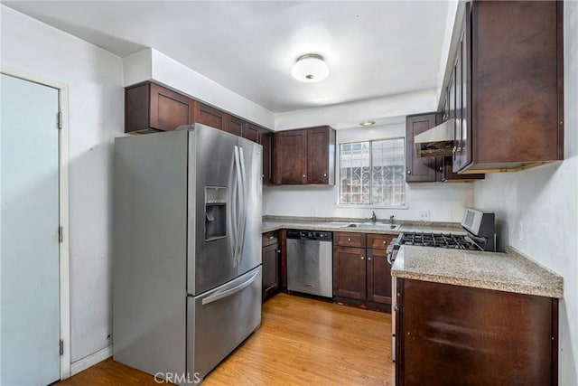 502 Tasman Ave, Pomona, CA 91767 - kitchen featuring appliances with stainless steel finishes, wall chimney range hood, dark brown cabinetry, light countertops, and light wood-style flooring