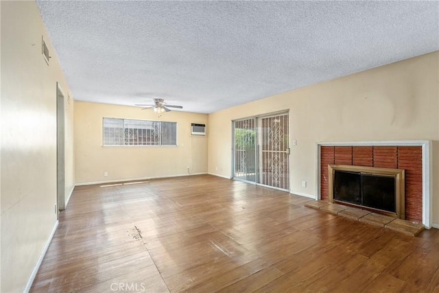 502 Tasman Ave, Pomona, CA 91767 - unfurnished living room with wood finished floors, ceiling fan, a textured ceiling, a fireplace, and a wall unit AC