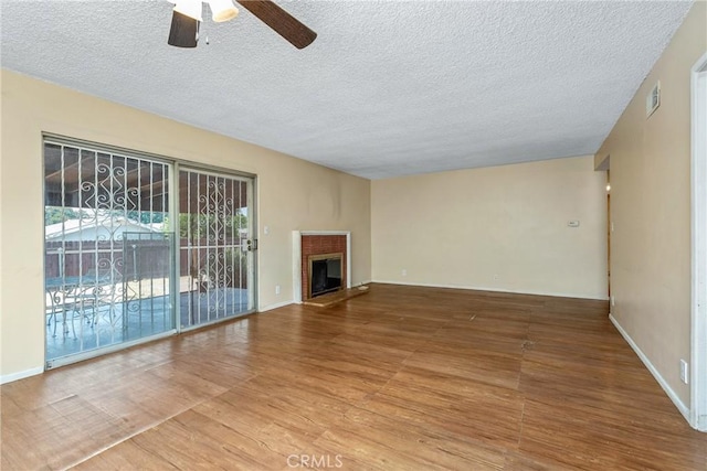 502 Tasman Ave, Pomona, CA 91767 - unfurnished living room with a ceiling fan, a textured ceiling, wood finished floors, and a brick fireplace