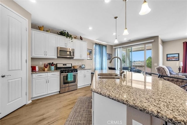 11444 River Run St, Apple Valley, CA 92308 - kitchen with stainless steel appliances, white cabinets, light wood-style floors, decorative light fixtures, and recessed lighting