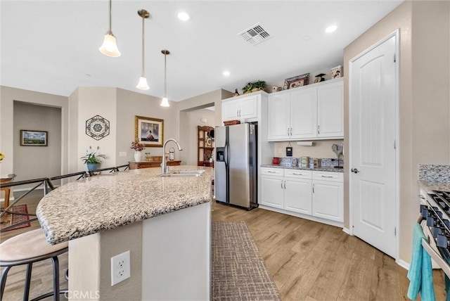 11444 River Run St, Apple Valley, CA 92308 - kitchen with stainless steel appliances, light wood finished floors, white cabinets, a breakfast bar, and hanging light fixtures