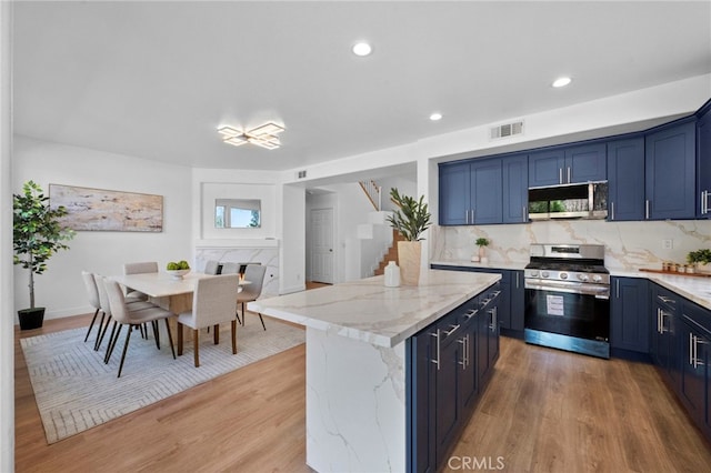 827 La Cadena Ln, Corona, CA 92879 - kitchen featuring stainless steel appliances, blue cabinets, light wood-style flooring, decorative backsplash, and light stone countertops