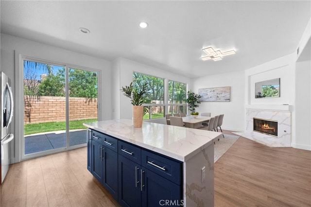 827 La Cadena Ln, Corona, CA 92879 - kitchen with light wood-type flooring, blue cabinetry, plenty of natural light, stainless steel fridge with ice dispenser, and recessed lighting