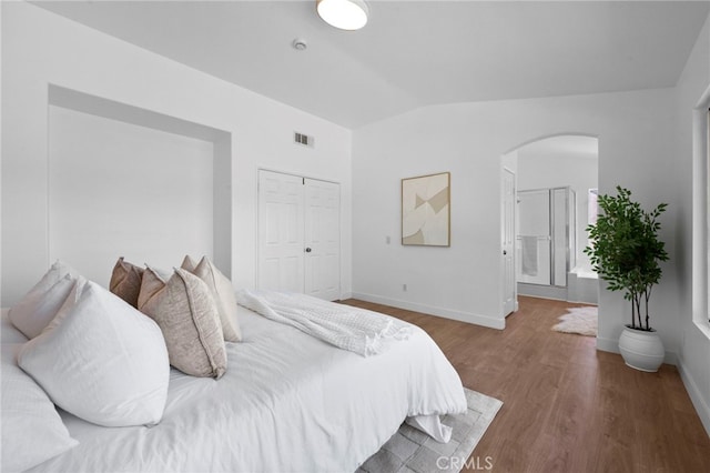 827 La Cadena Ln, Corona, CA 92879 - bedroom featuring arched walkways, vaulted ceiling, wood finished floors, a closet, and connected bathroom