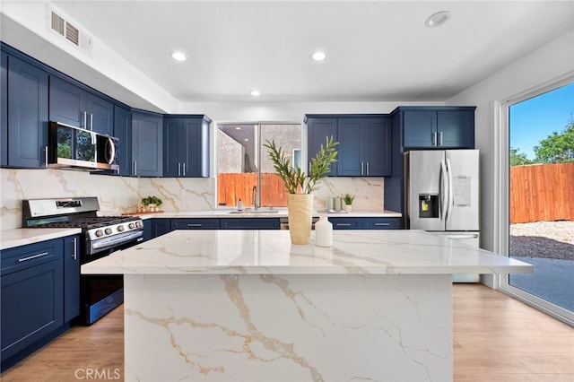 827 La Cadena Ln, Corona, CA 92879 - kitchen with stainless steel appliances, blue cabinets, recessed lighting, light stone counters, and a center island